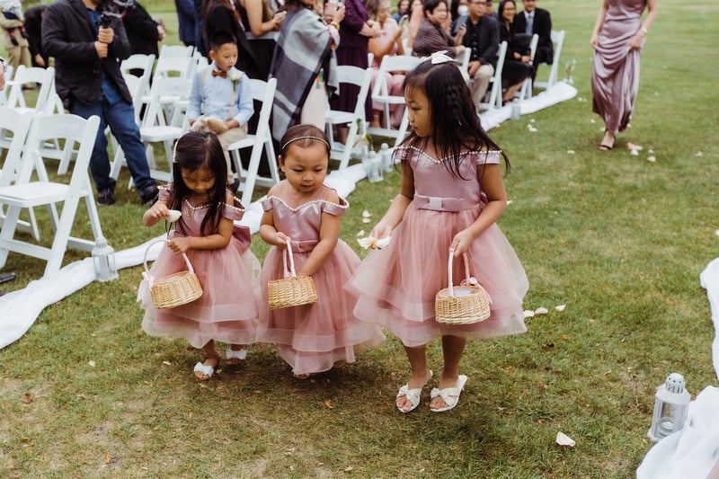 Three flower girls in dresses holding baskets of flower petals at a wedding. This image portrays children taking part in a wedding, to depict their absence in weddings that will never be.